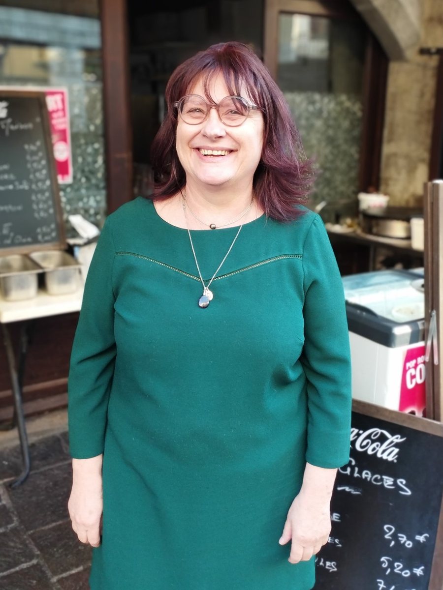 Isabelle, tout sourire devant l'entrée de la taverne sous les arcades